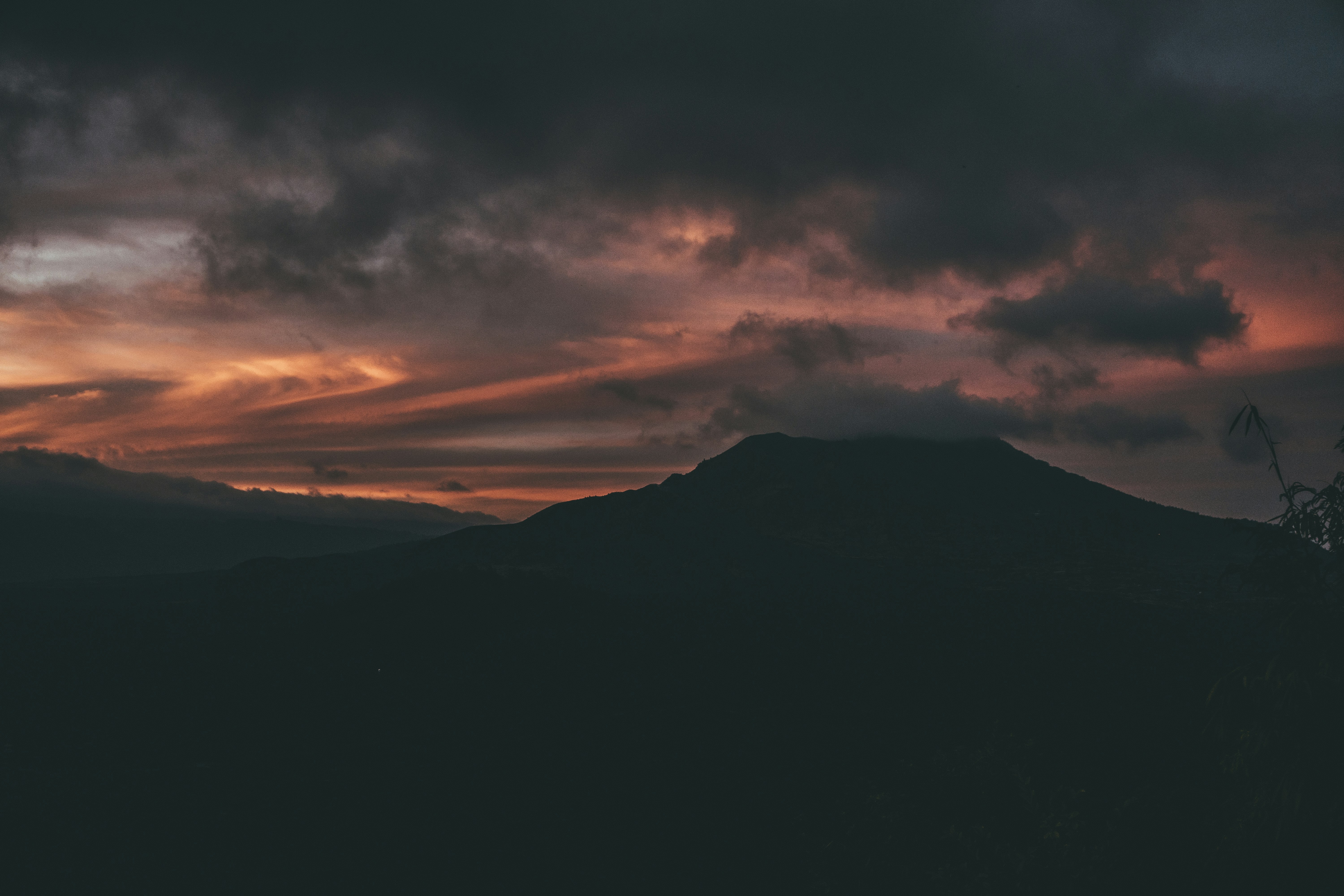 silhouette of mountain under cloudy sky during sunset